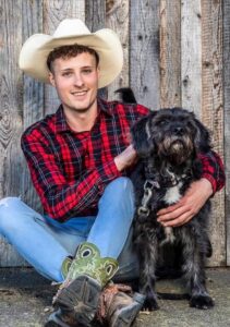 Johannes Höfinger, bekannt aus Bauer sucht Frau International, mit Cowboyhut und seinem Hund vor einer Scheune